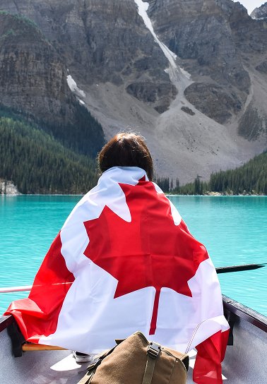 Persona sentada en una barca, envuelta en una bandera canadiense. Nuestro servicio de casillero inte