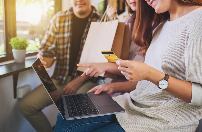 Mujer con laptop y tarjeta de crédito, hombre en el fondo Recibir paquetes con facilidad gracias a Á