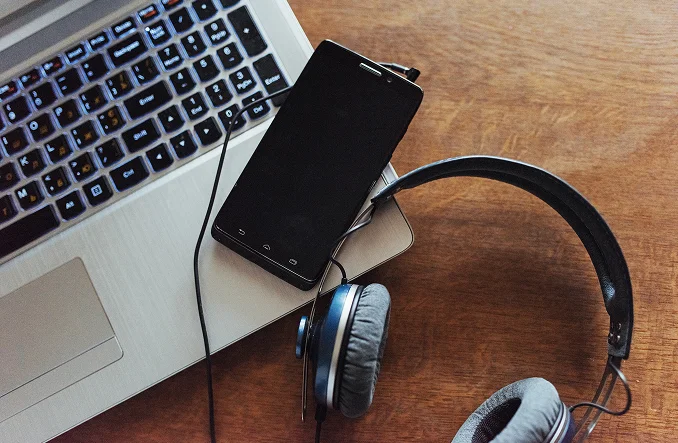 Laptop, smartphone y auriculares sobre una mesa de madera Recibir paquetes en Estados Unidos con Ági