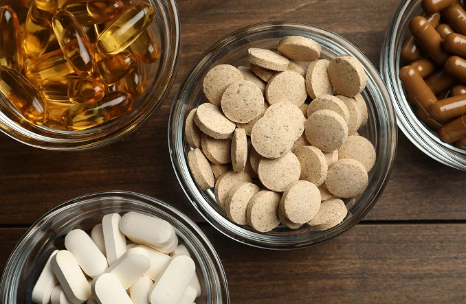 Familia de vitaminas y suplementos en bowls de vidrio sobre una mesa de madera Nuestro servicio de c